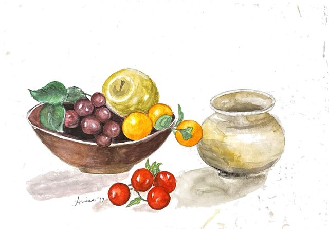 A bowl of grapes and round fruit sits beside a pale pot and a cluster of red tomatoes.