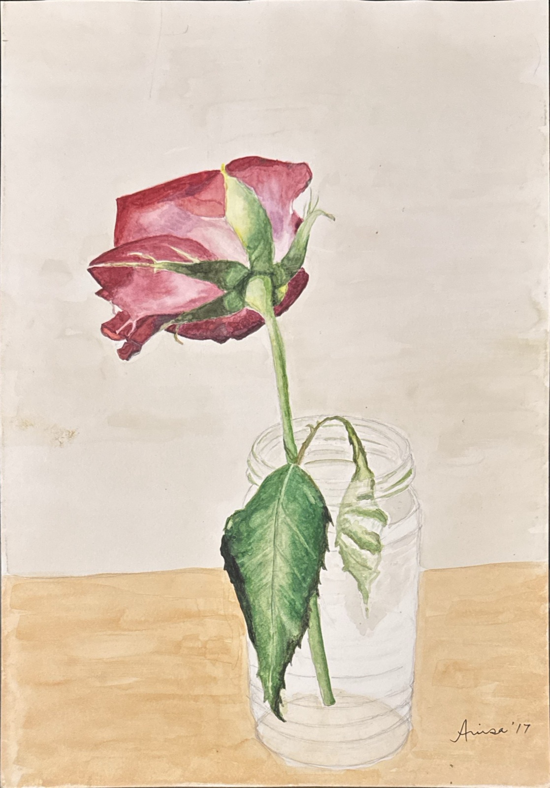 A single deep pink rose leans above a clear glass bottle, its green leaves falling beside the stem.