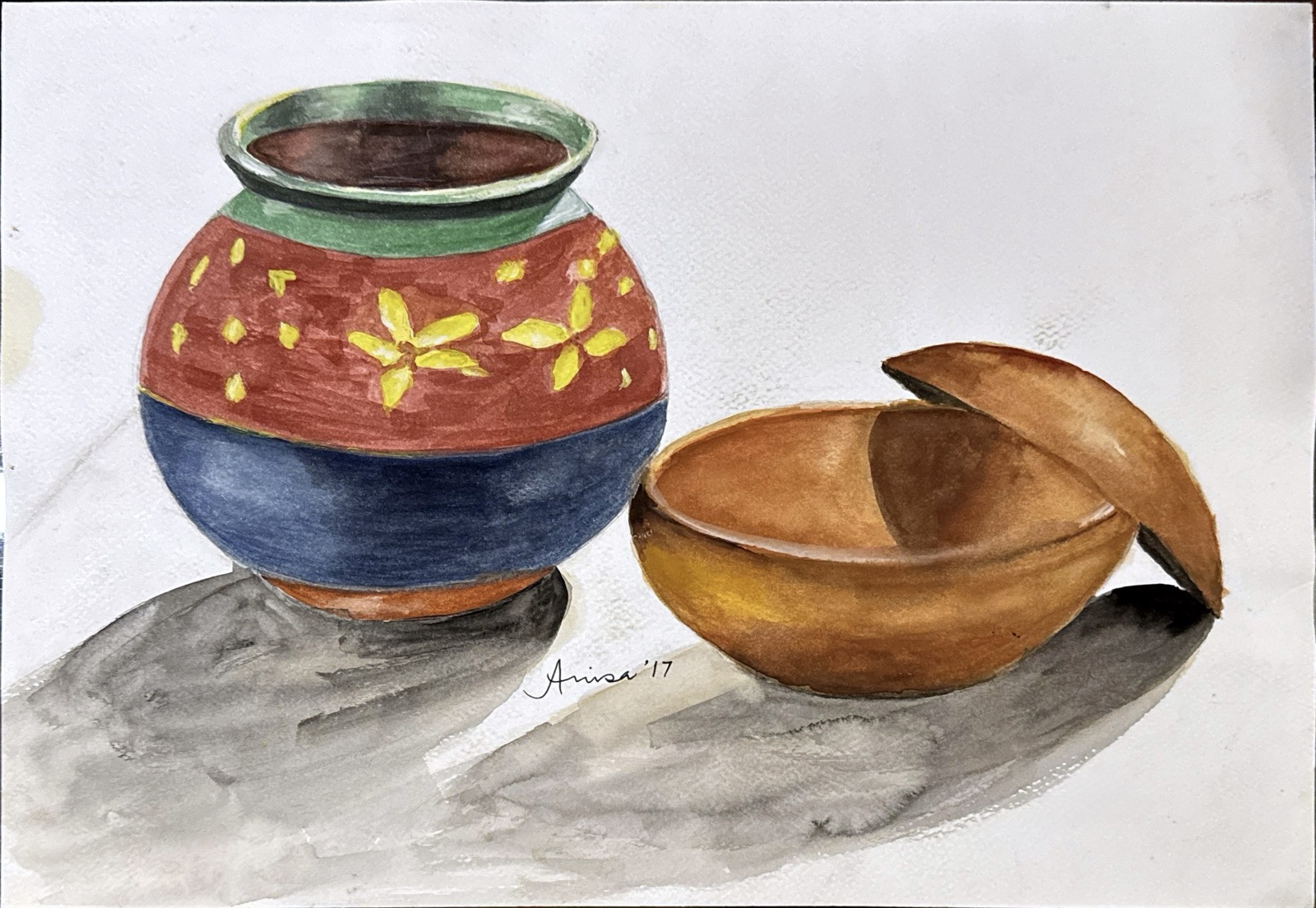 A round pot painted in red, blue and yellow stands beside a wooden bowl with its lid tilted open.