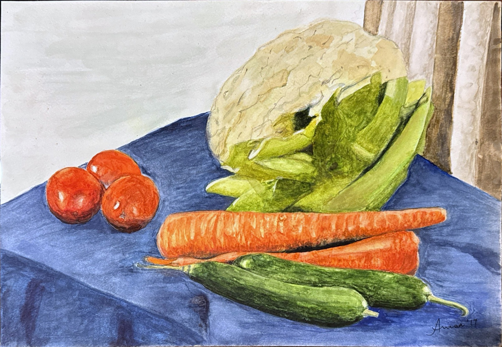 Cauliflower, carrots, cucumbers and red tomatoes are arranged on a deep blue cloth.